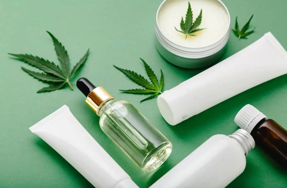 CBD skincare and wellness products with hemp leaves on a green background