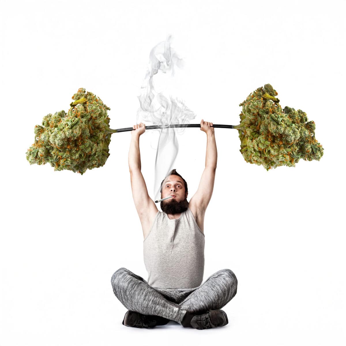 Man lifting a cannabis barbell while sitting cross-legged, symbolizing CBD use in fitness and recovery.