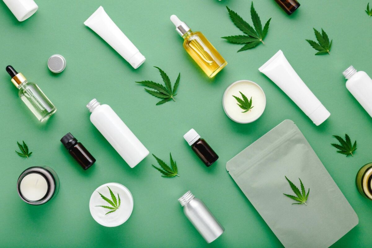 Selection of CBD, CBG, and THCa beauty and wellness products arranged on a green background