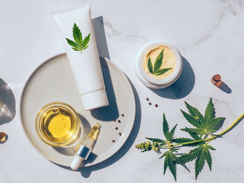 Minimalist dropper vial labeled CBD with soft-focus botanical elements in the background