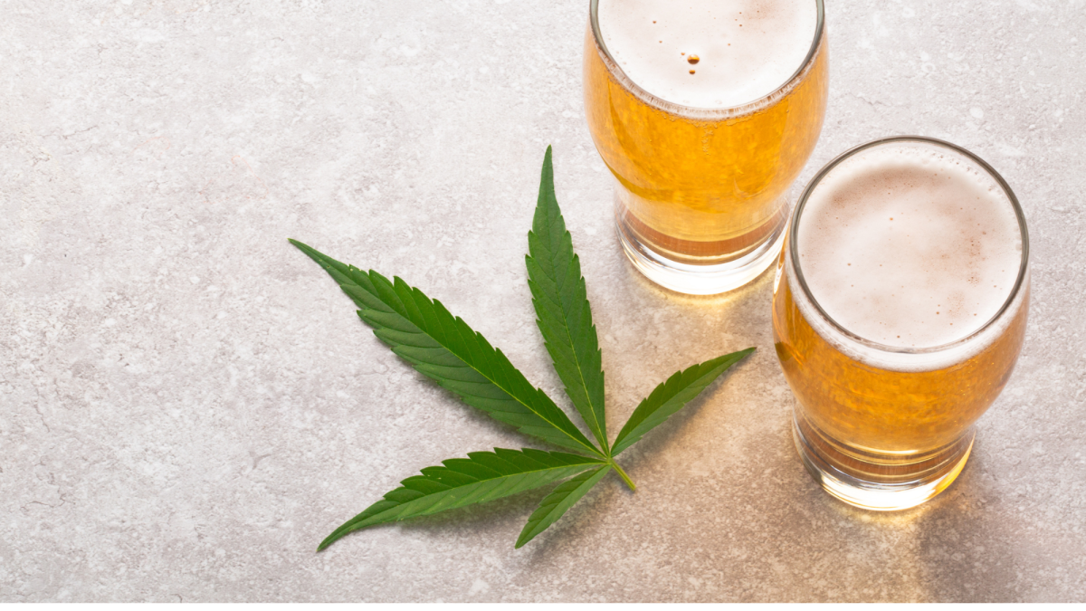 Glass of cannabis drink beside a beer bottle on a wooden table — comparing weed and alcohol consumption